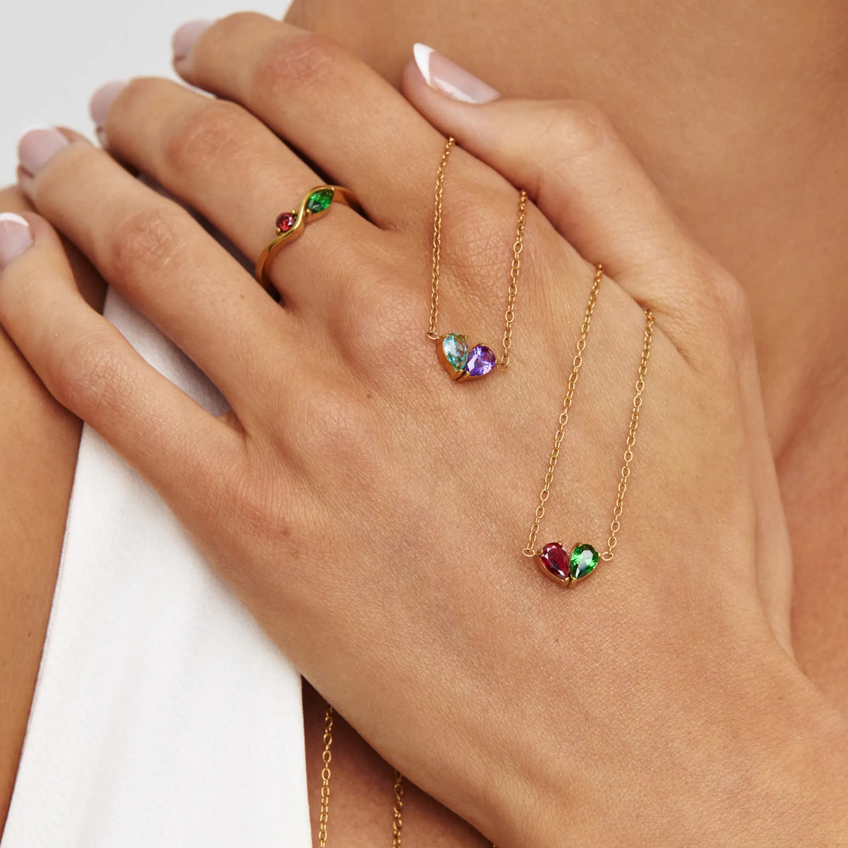 Two Duo Heart Necklaces with different birthstone pairs held in hand
